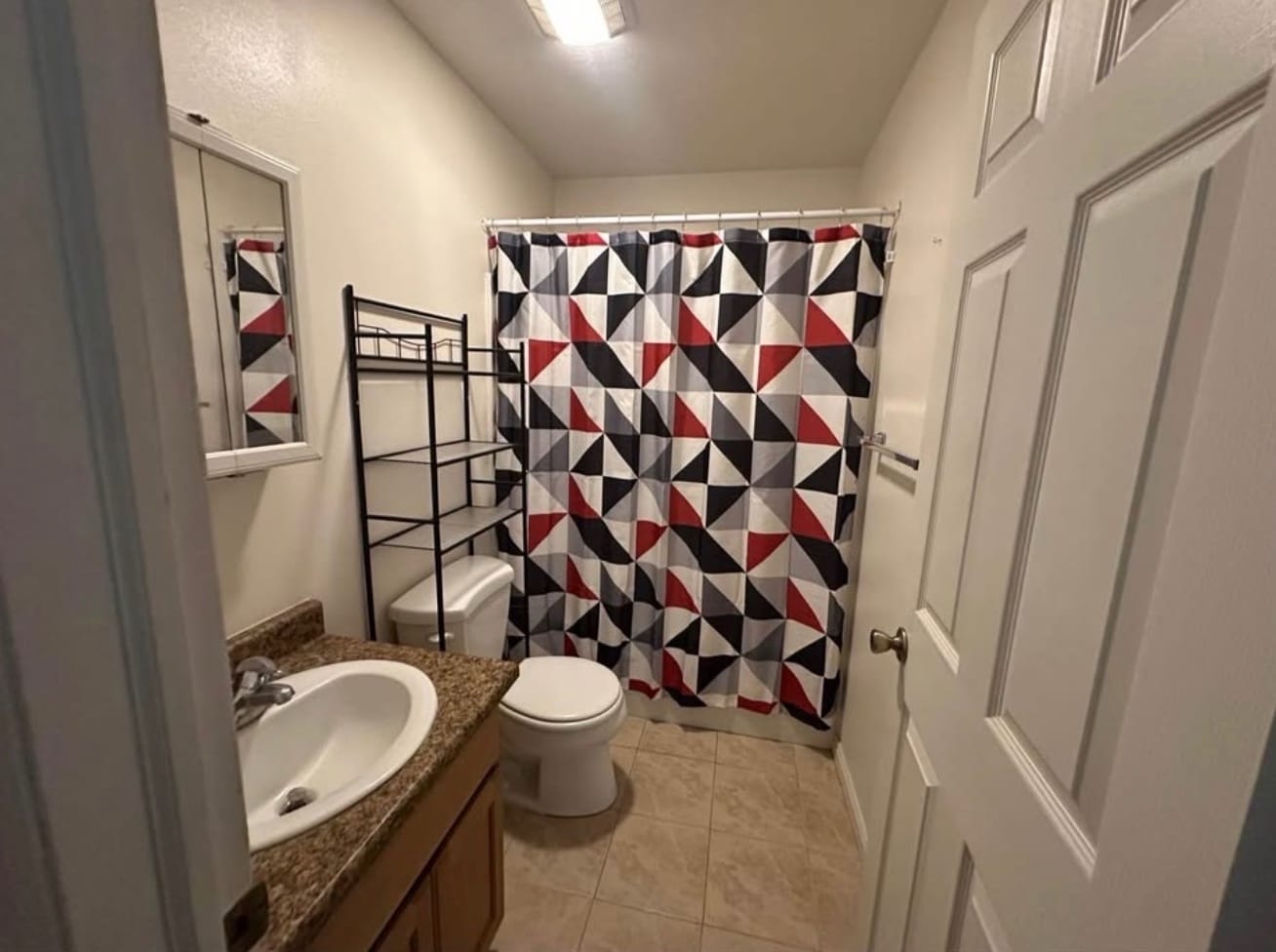 Bathroom with a shower, a vanity with a granite-look counter, a medicine cabinet and a tiled floor