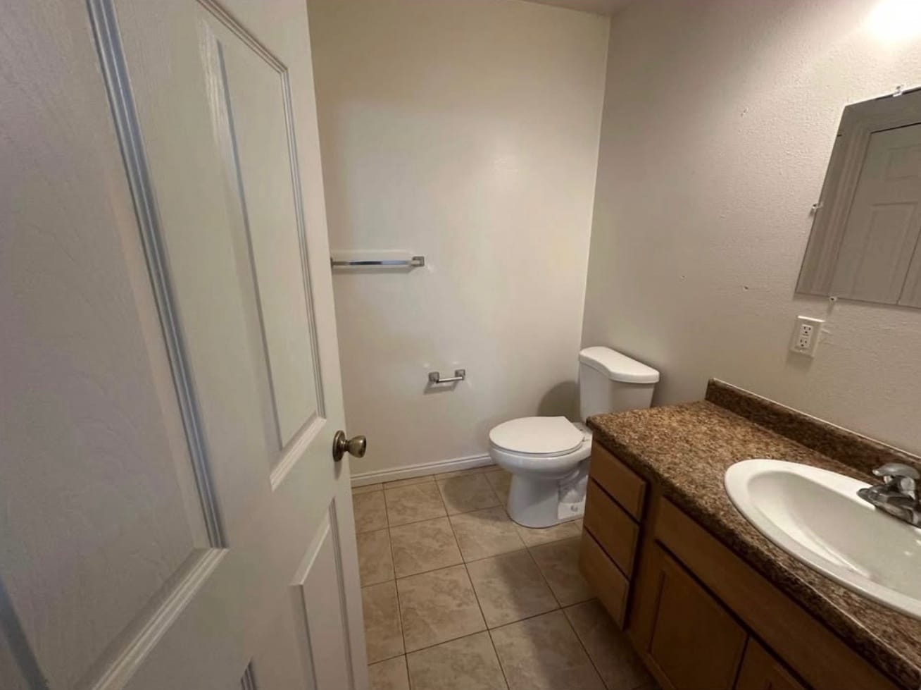 The second bathroom, with a vanity, a wall mirror and a tiled floor