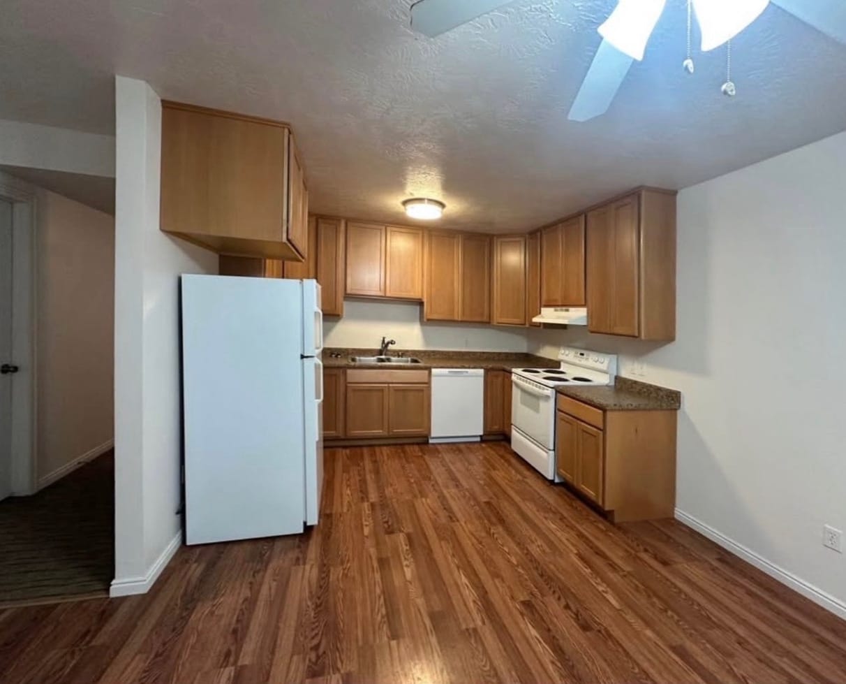 Kitchen in a Clover Creek Heights apartment, with oak cabinets, a white refrigerator and range, and wood-look flooring