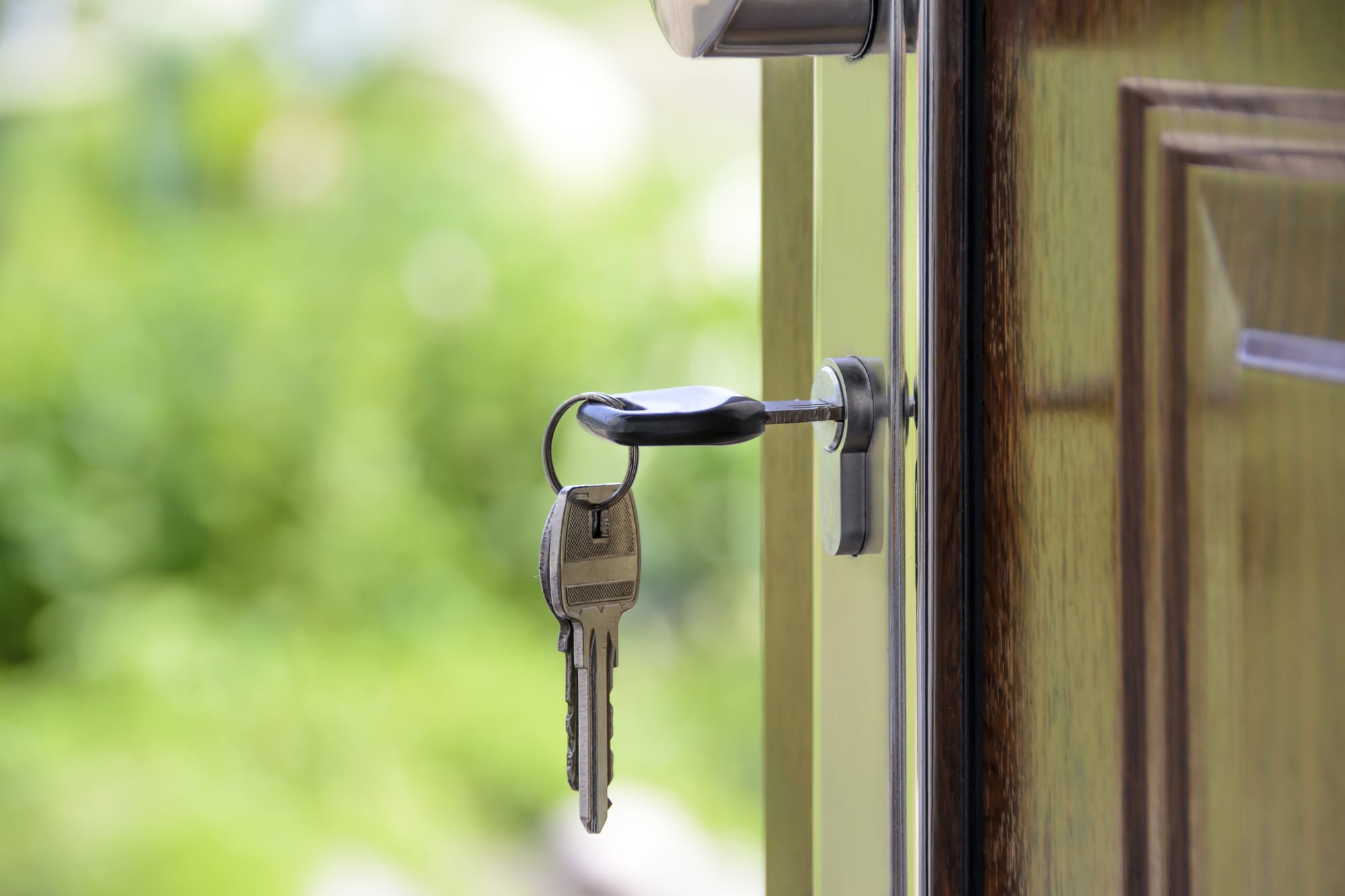 A set of house keys hanging from the lock of an open front door