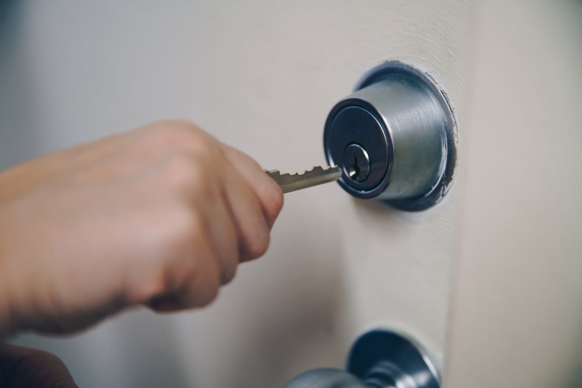 A hand turning a key in a front-door deadbolt